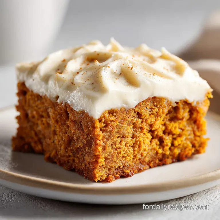 A square of spiced pumpkin bar, glistening with rich cream cheese frosting, dusted with cinnamon.