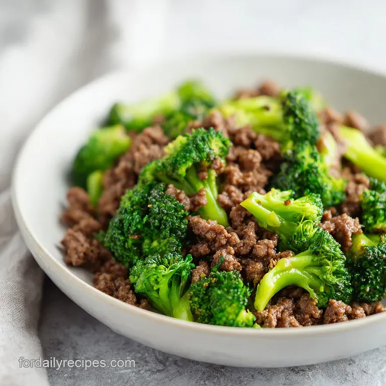 Steaming ground beef and broccoli served over fluffy white rice, garnished with vibrant green scallions in a white bowl.